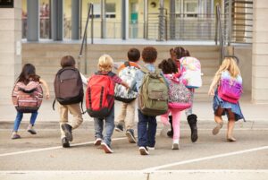 A group of elementary school aged kids arrive at the entrance to school