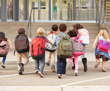 A group of elementary school aged kids arrive at the entrance to school