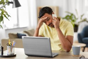 Stressed person on phone and laptop