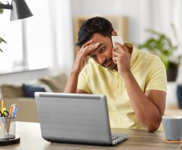 Stressed person on phone and laptop