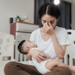 Tired stressed mom holding sleeping baby
