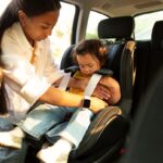 Mom buckling toddler into carseat