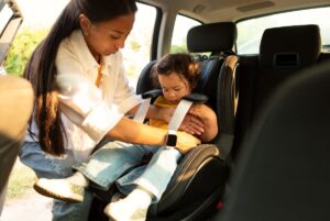 Mom buckling toddler into carseat