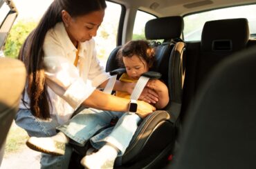 Record high waitlists for child care assistance have shut women out of work, promotions Mom buckling toddler into carseat