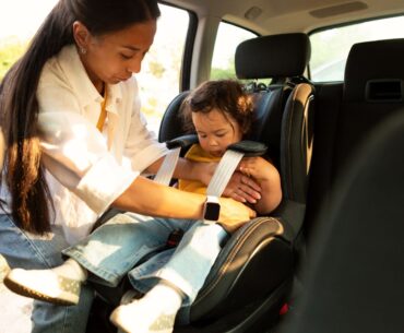 Mom buckling toddler into carseat