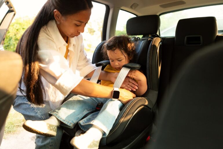 Mom buckling toddler into carseat