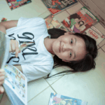 Girl lying with comic books and graphic novels