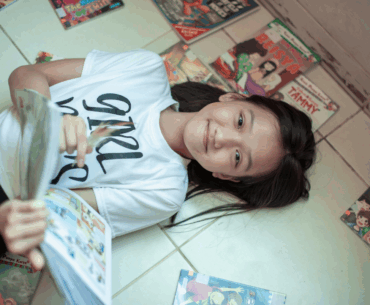 Girl lying with comic books and graphic novels